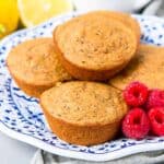 Lemon poppy seed muffins and raspberries on a blue and white plate.