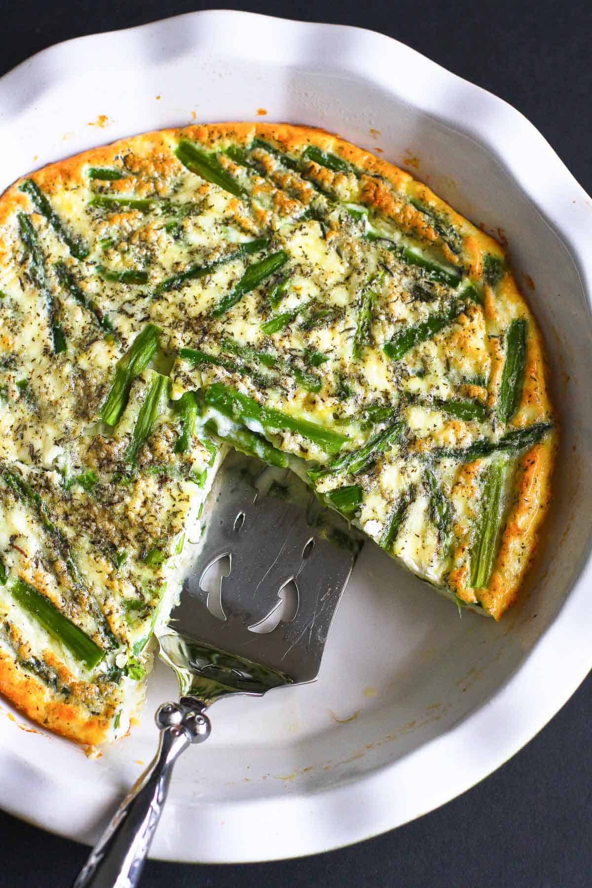 Crustless asparagus quiche and silver server in a white pie dish.