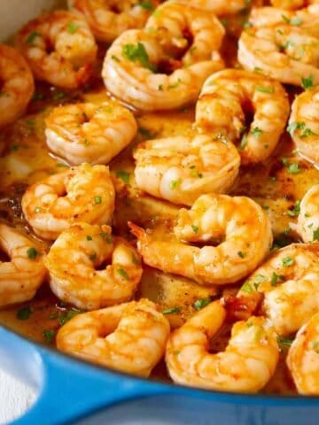 Cooked paprika shrimp and sauce in a large blue skillet.