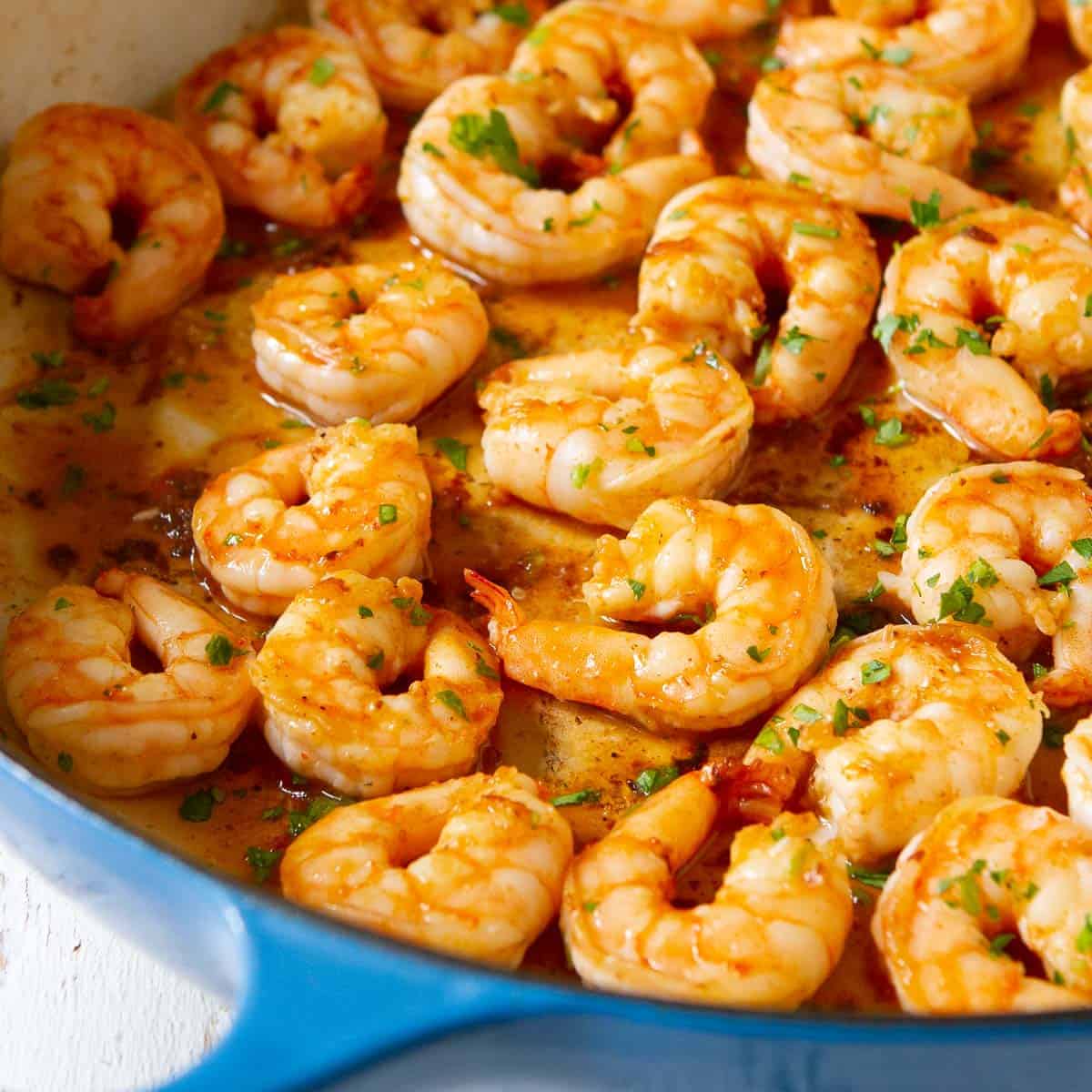 Cooked paprika shrimp and sauce in a large blue skillet.
