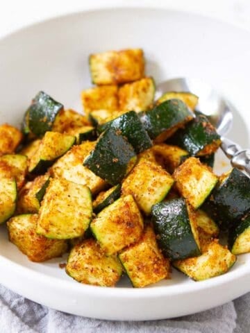 Air fried zucchini pieces in a white bowl.