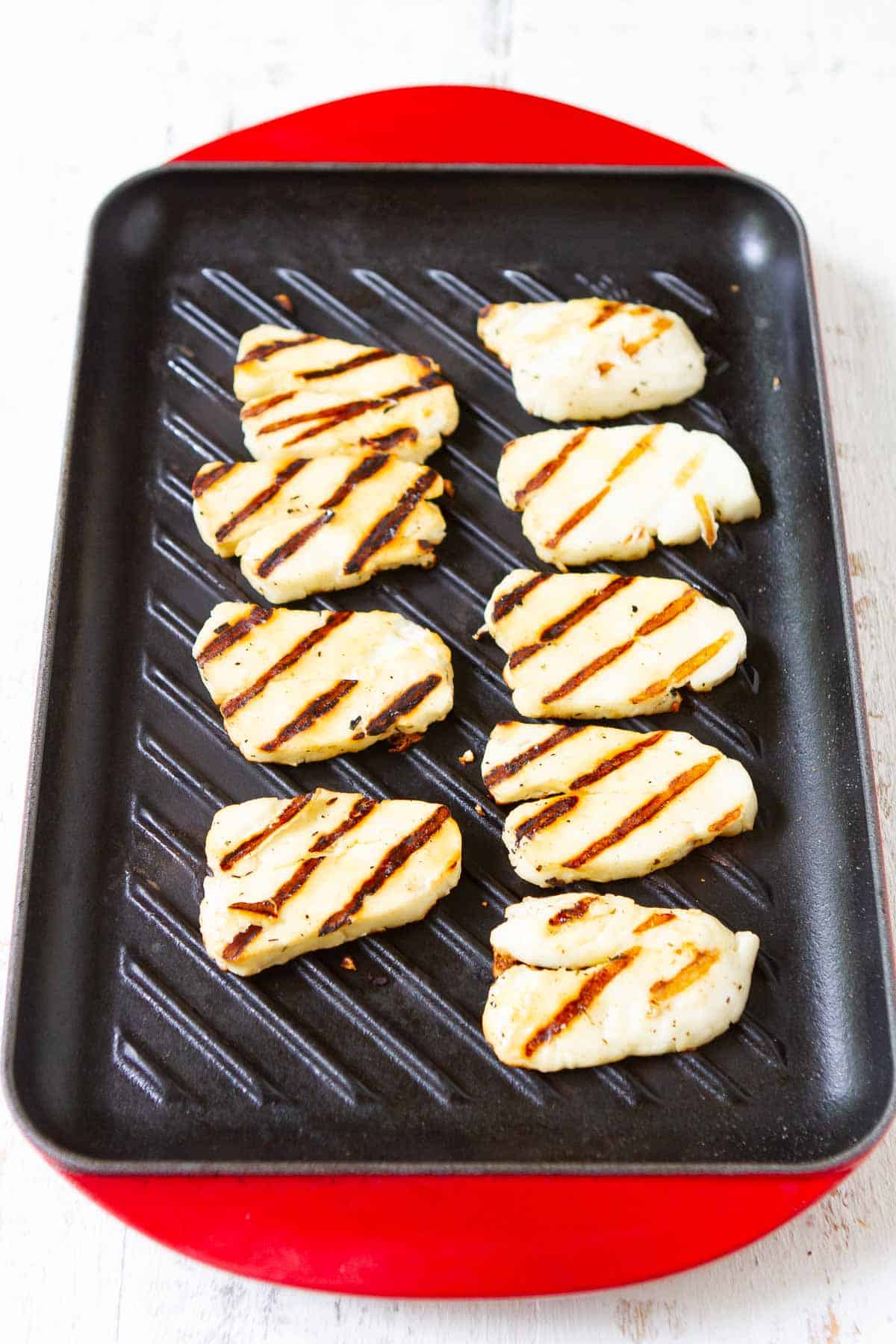 Grilled halloumi cheese slices on a cast iron grill.
