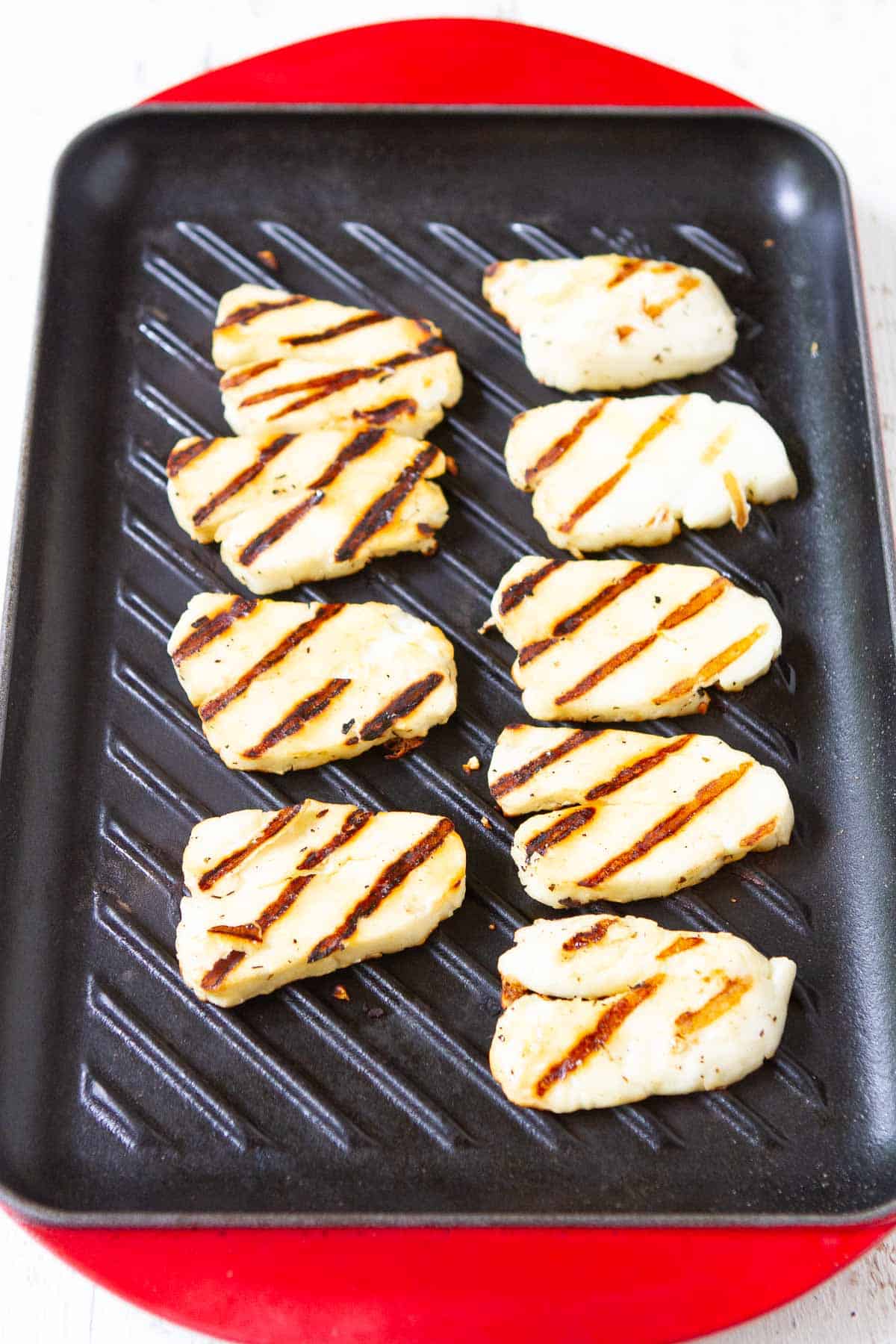 Grilled halloumi cheese on a rectangular grill pan.