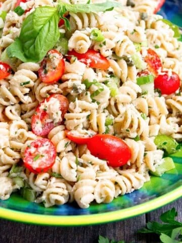 Tuna pasta salad with grape tomatoes in a blue-green bowl.