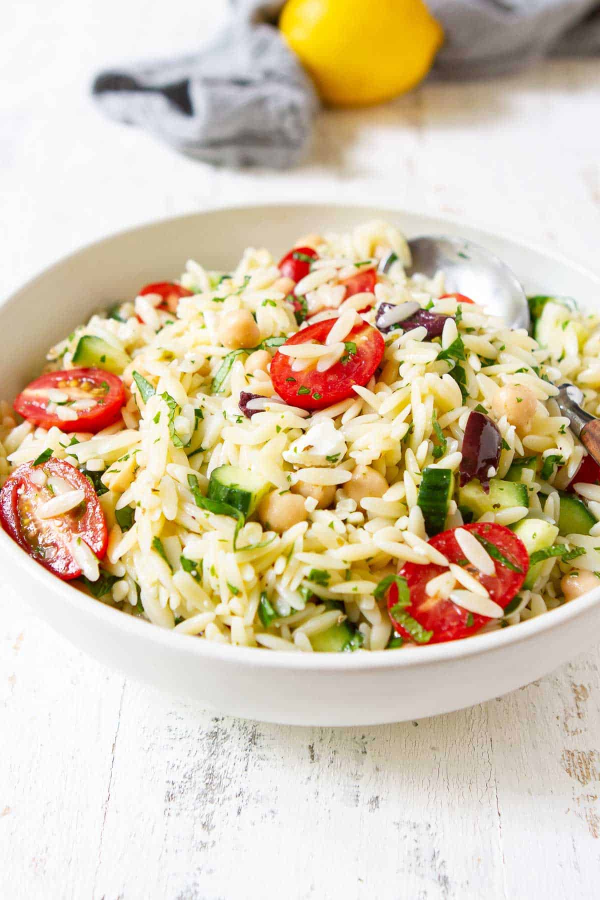 Pasta salad with chickpeas and tomatoes in a white bowl.