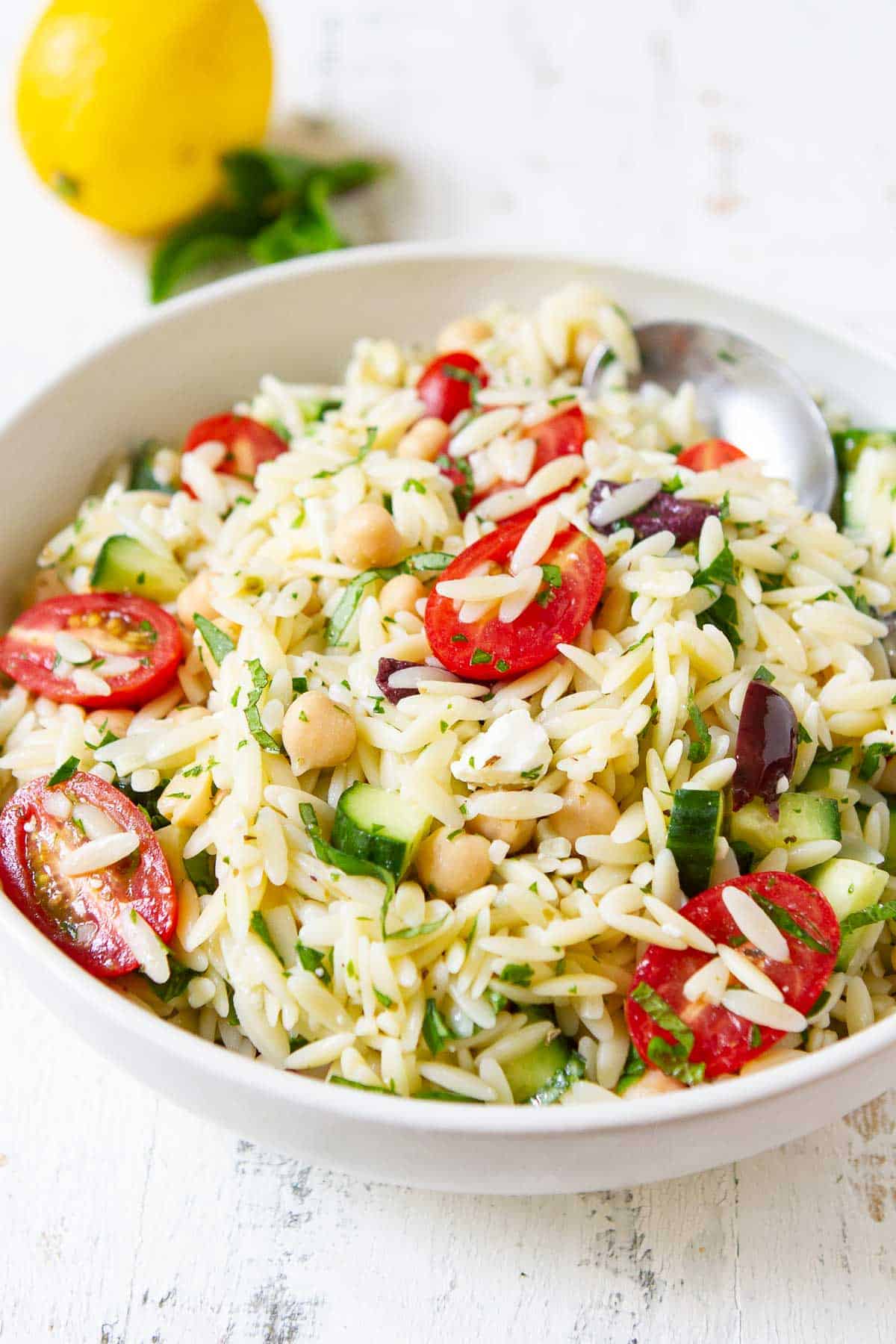 Orzo pasta salad with vegetables in a white bowl.