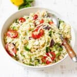 Orzo pasta salad with vegetables in a white bowl.