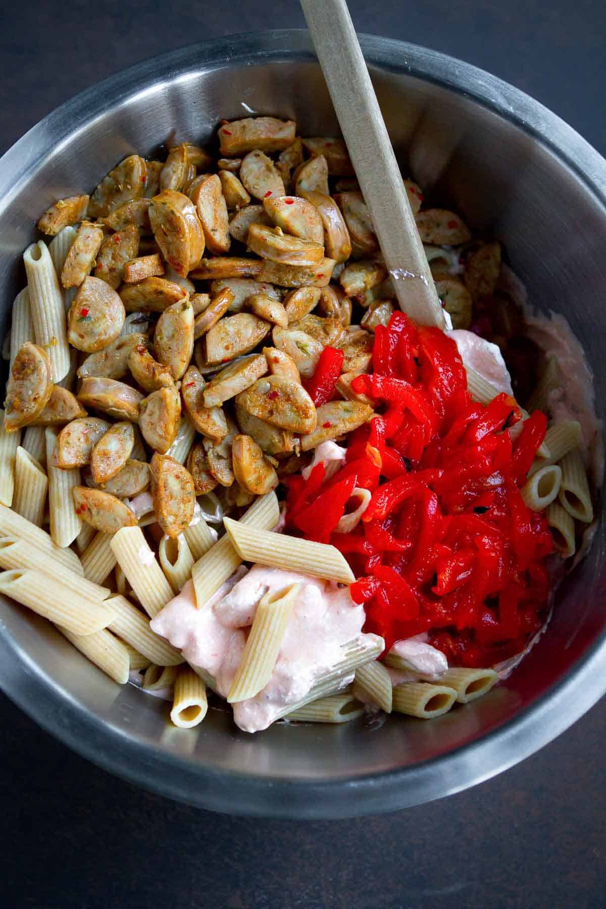Cooked pasta, sausage and roasted peppers in a large mixing bowl.