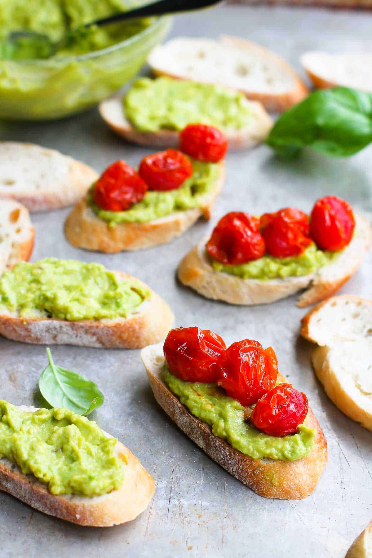 Crostini with guacamole and tomatoes on a baking sheet.