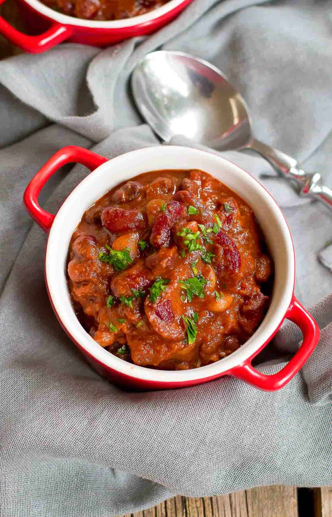 Meatless bean chili in a small red bowl, set on a gray napkin.