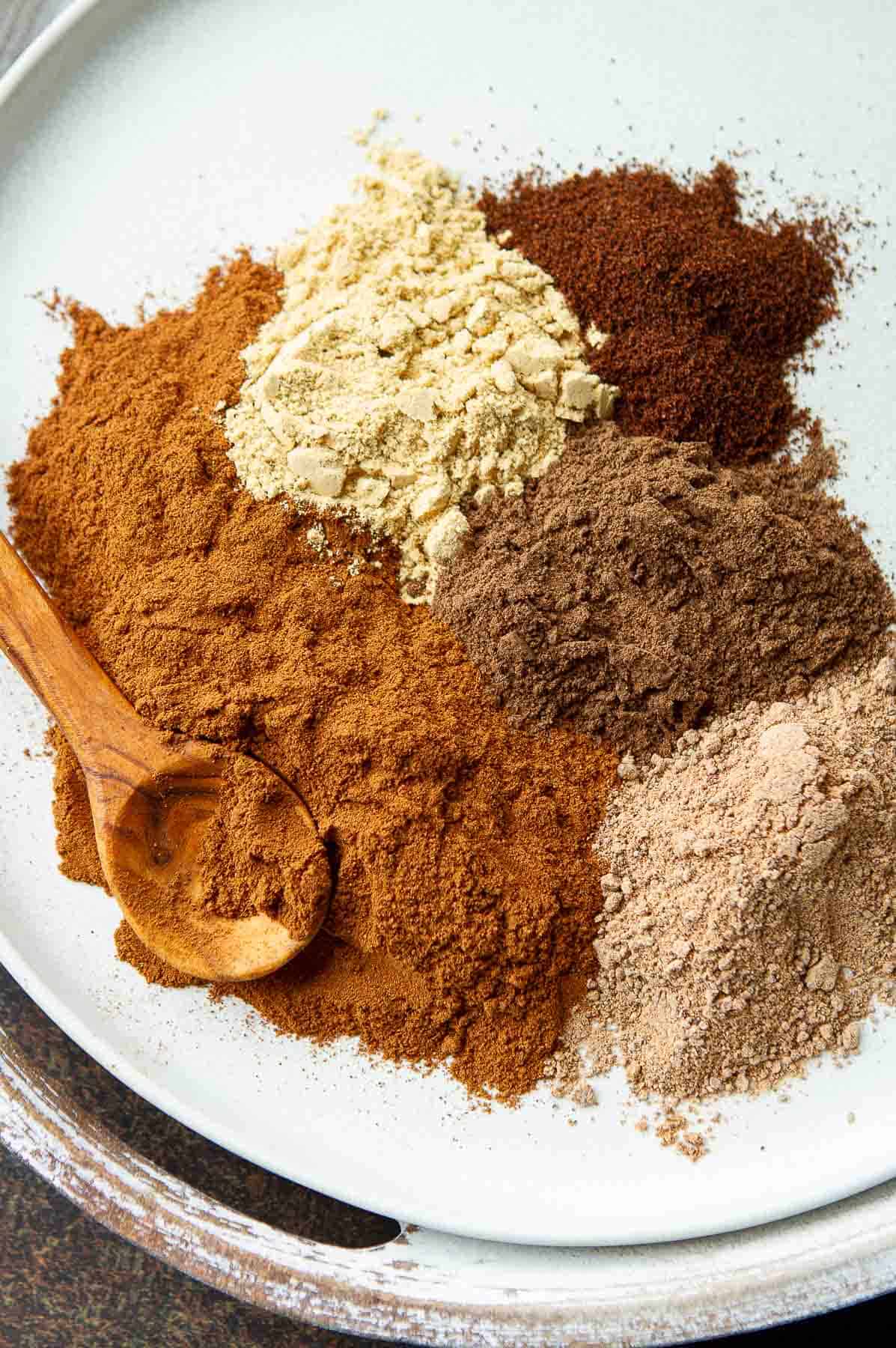 Piles of five spices on a white plate.
