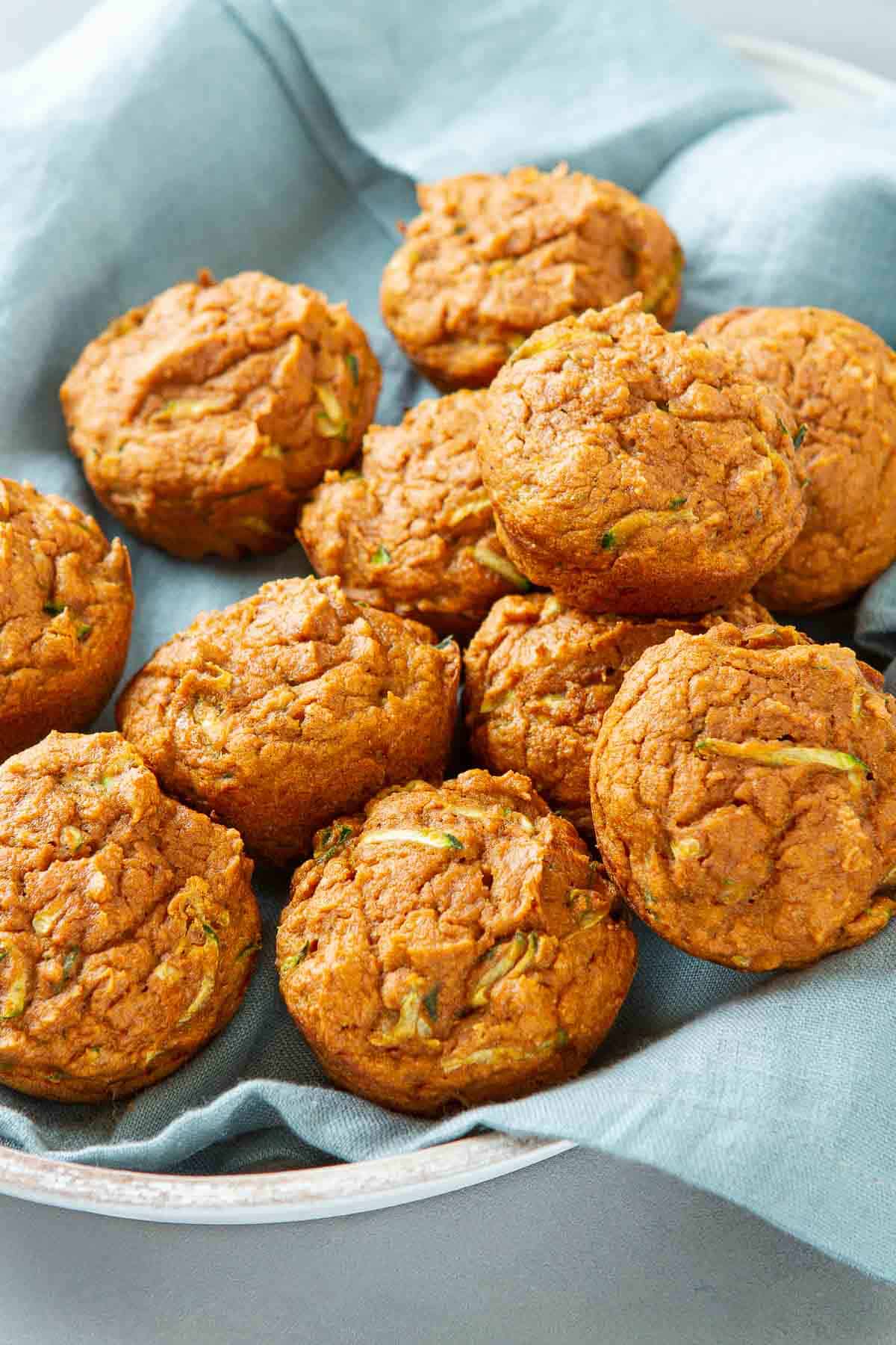 Zucchini pumpkin muffins on a white tray with a light blue napkin.