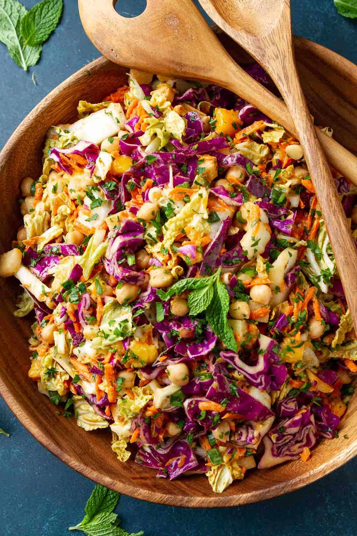 Slaw with chickpeas and peanut dressing in a large wooden salad bowl.