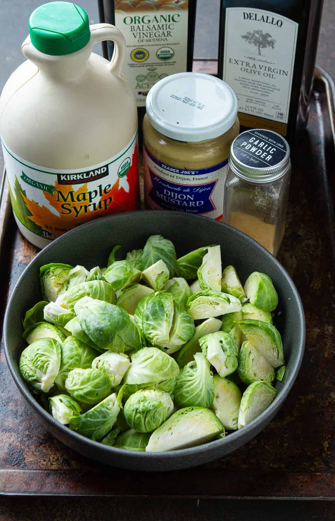 Brussels sprouts, maple syrup, Dijon mustard, garlic powder, balsamic vinegar and olive oil on a baking sheet.