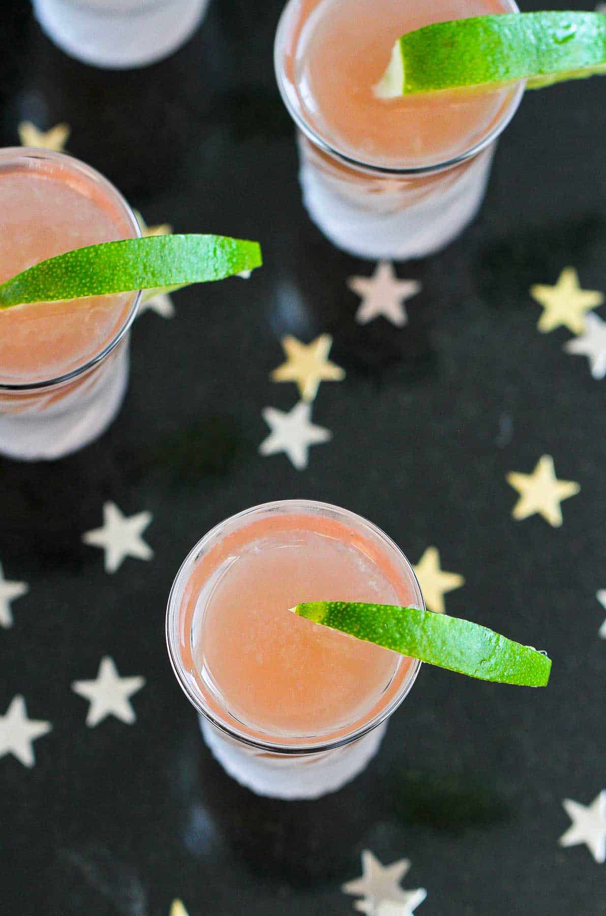Overhead photo of cranberry juice vodka shots, on a black background with stars.
