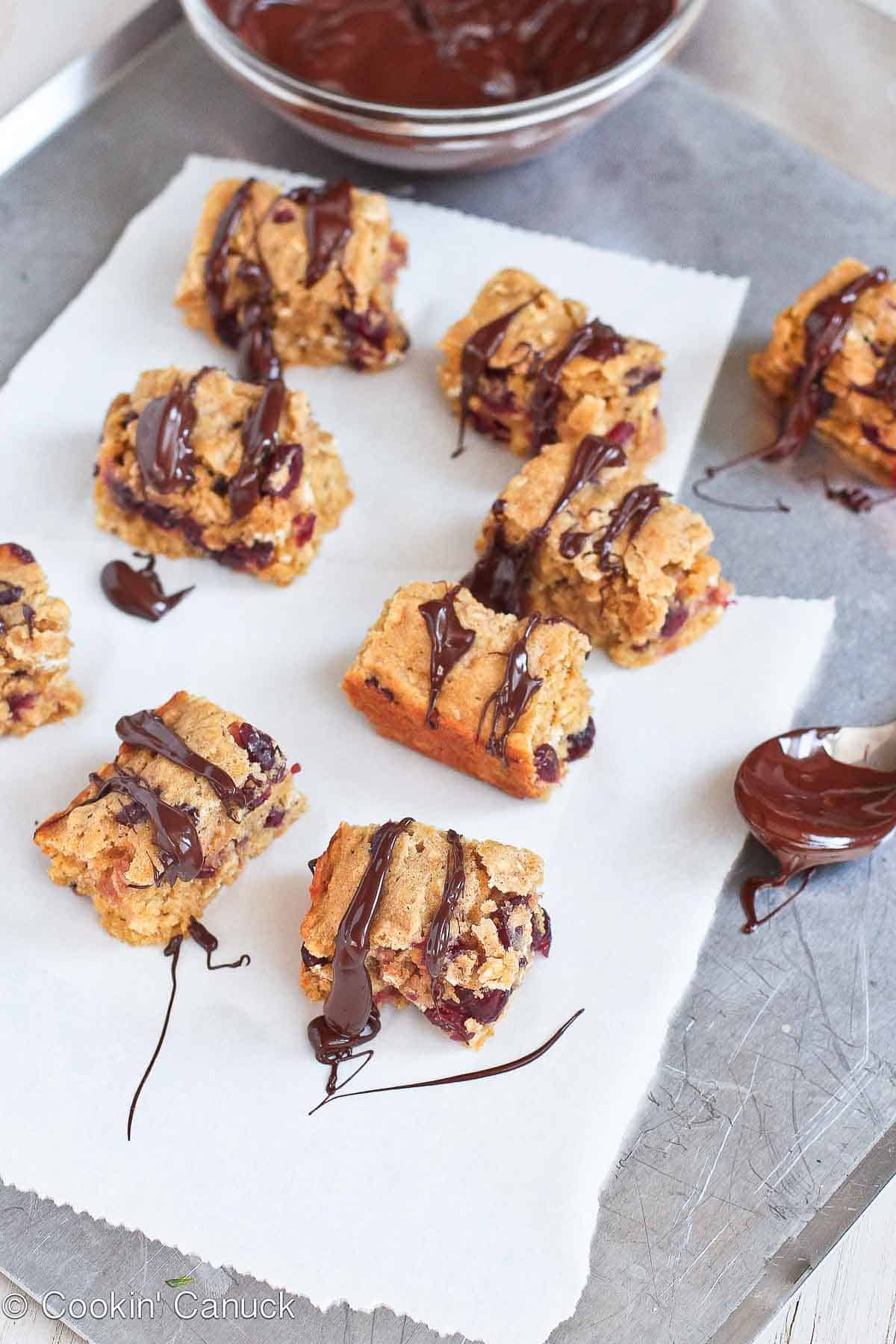Oatmeal bars with cranberries on a baking sheet, drizzled with chocolate.