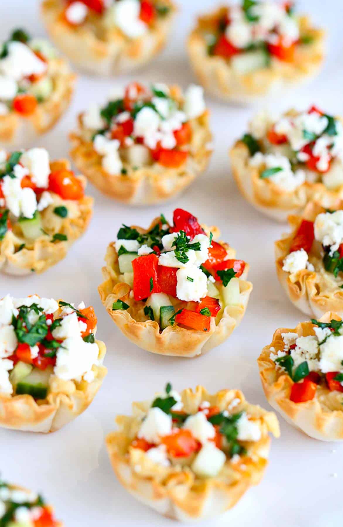 Mediterranean phyllo bites on a white platter. Filled with cucumber, peppers and cheese.