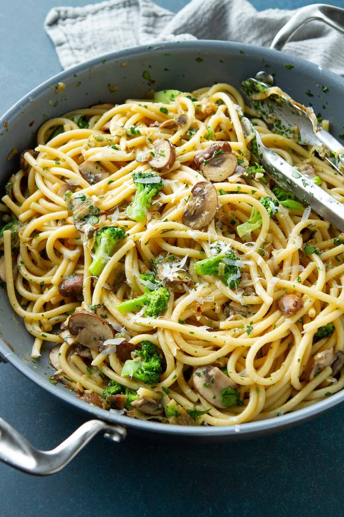 Nonstick skillet filled with noodles, broccoli and mushrooms.