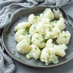 Steamed cauliflower florets on a gray plate.