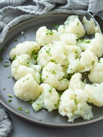 Steamed cauliflower florets on a gray plate.