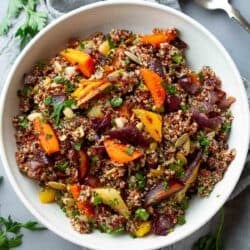 Quinoa salad with roasted carrots and onions in a white bowl.