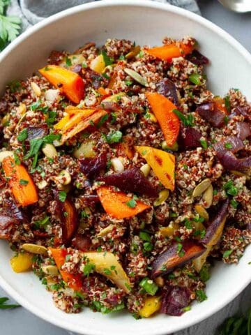 Quinoa salad with roasted carrots and onions in a white bowl.