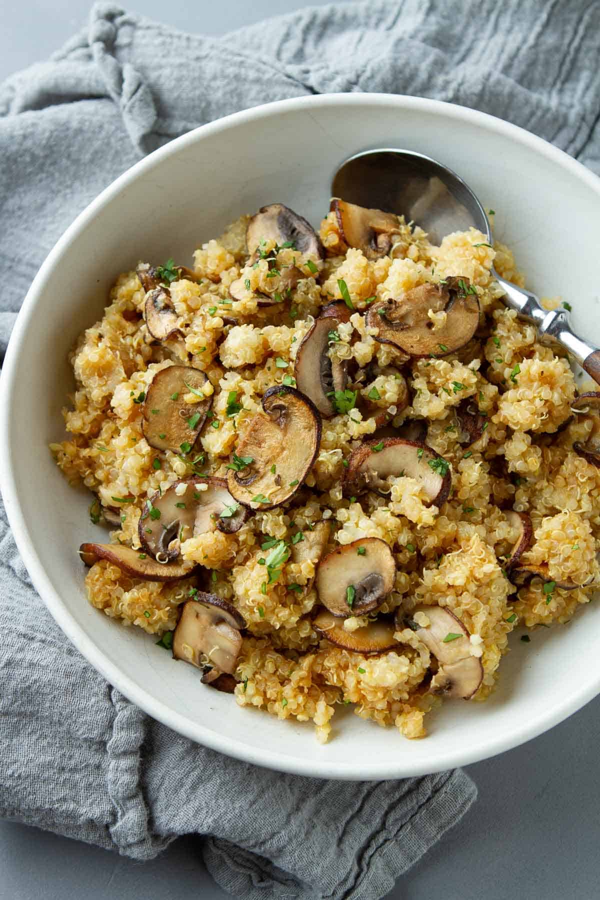 Quinoa with mushrooms in a white bowl.