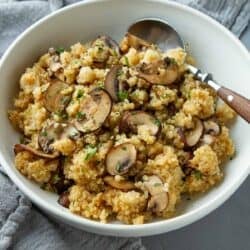 Mushrooms and quinoa in a white bowl with a spoon.