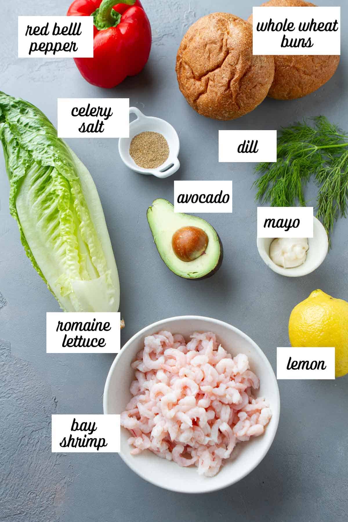 Labeled ingredients for shrimp avocado sandwich on a gray background.