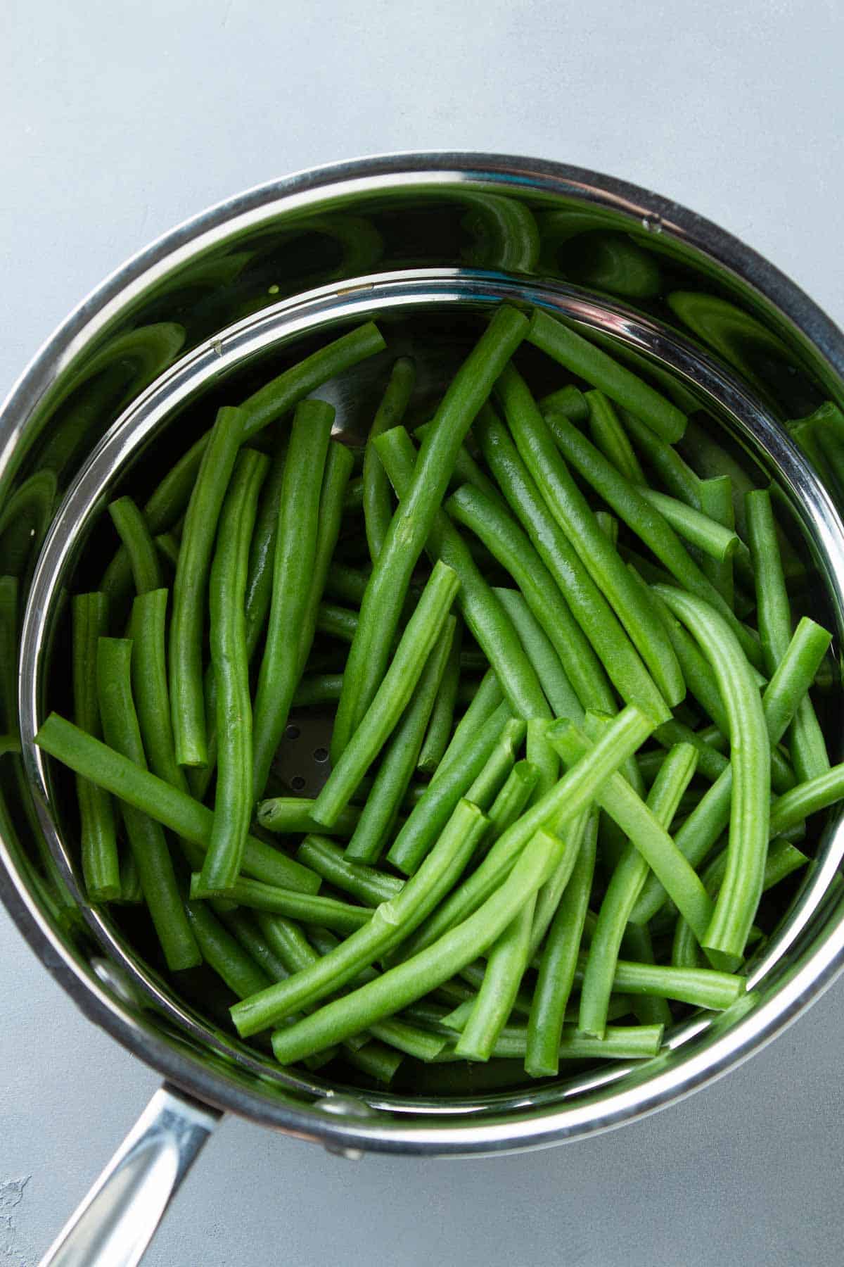Green beans in a double boiler-style steamer.