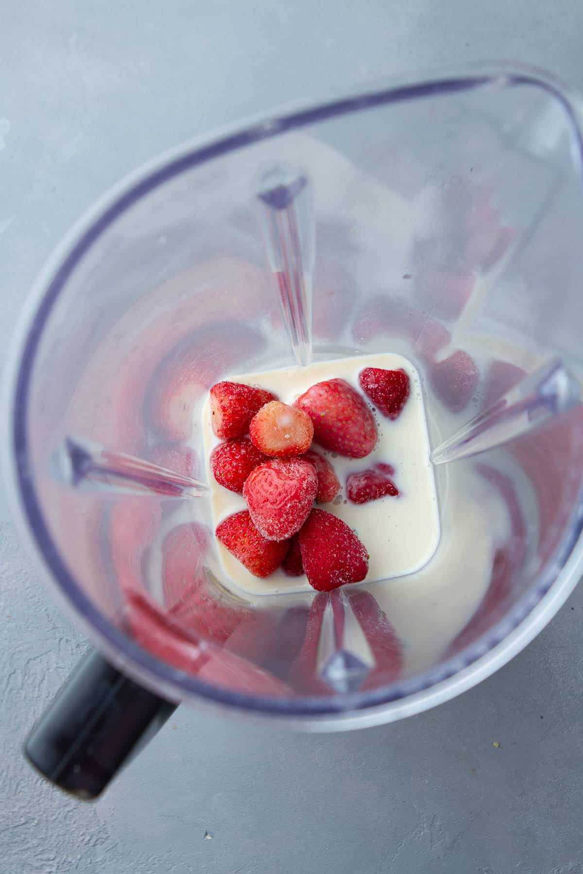 Strawberries and soy milk in a blender.
