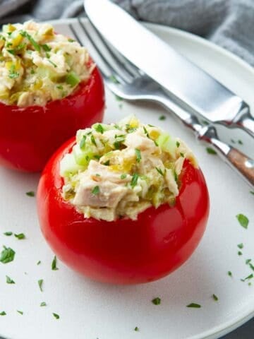 Tomatoes stuffed with tuna salad on a white plate.