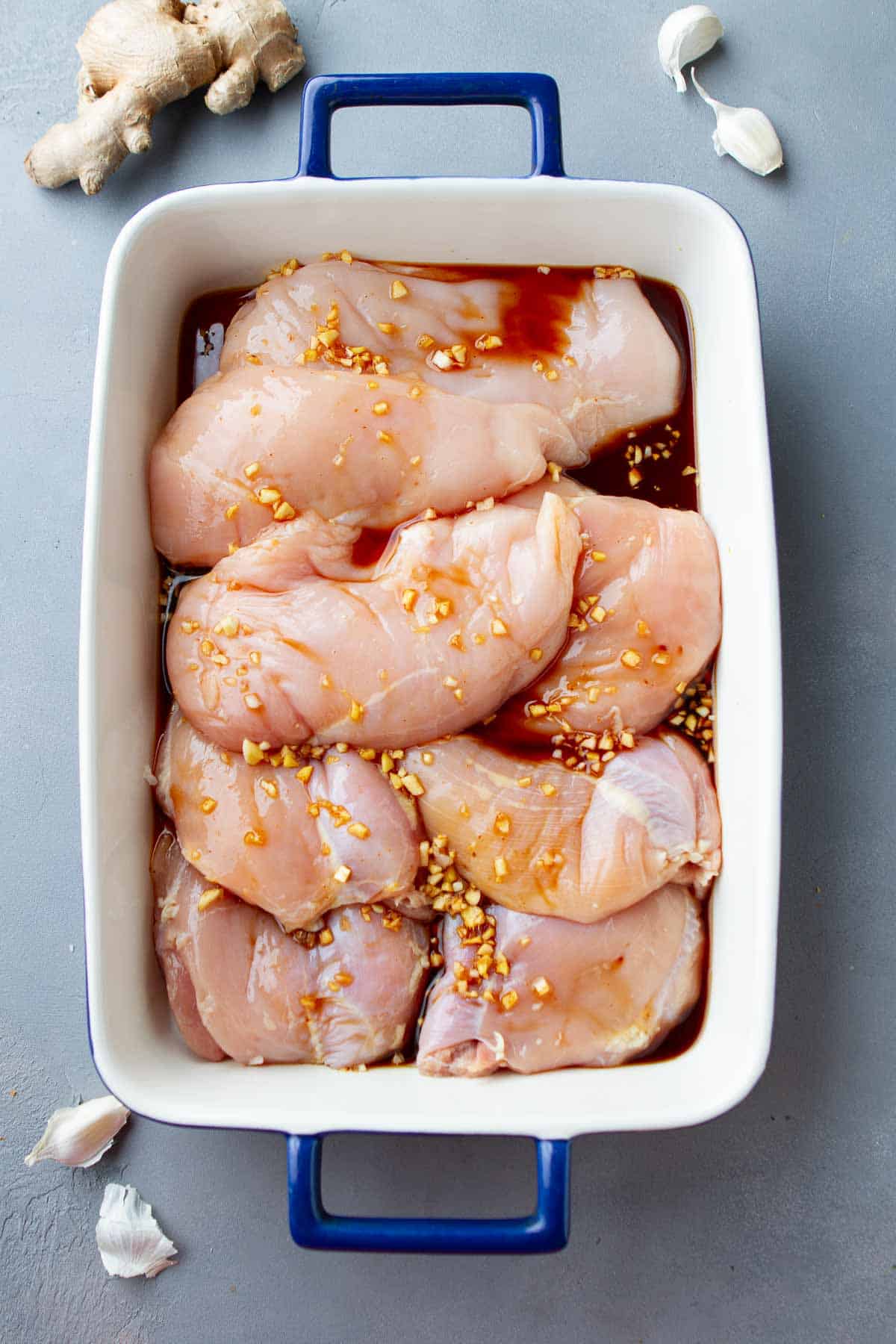 Chicken breasts marinating in a soy sauce marinade.
