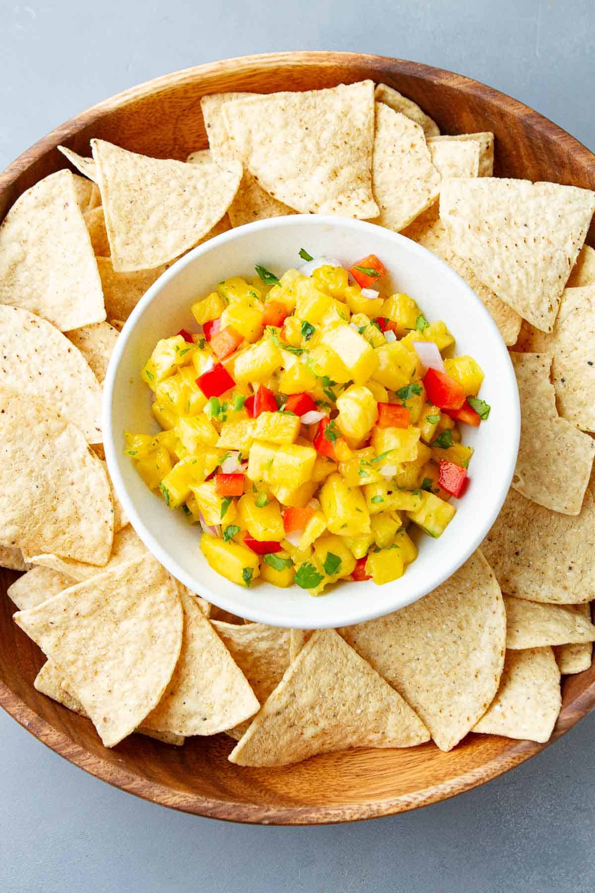 Chopped pineapple and red pepper in a bowl, with tortilla chips.