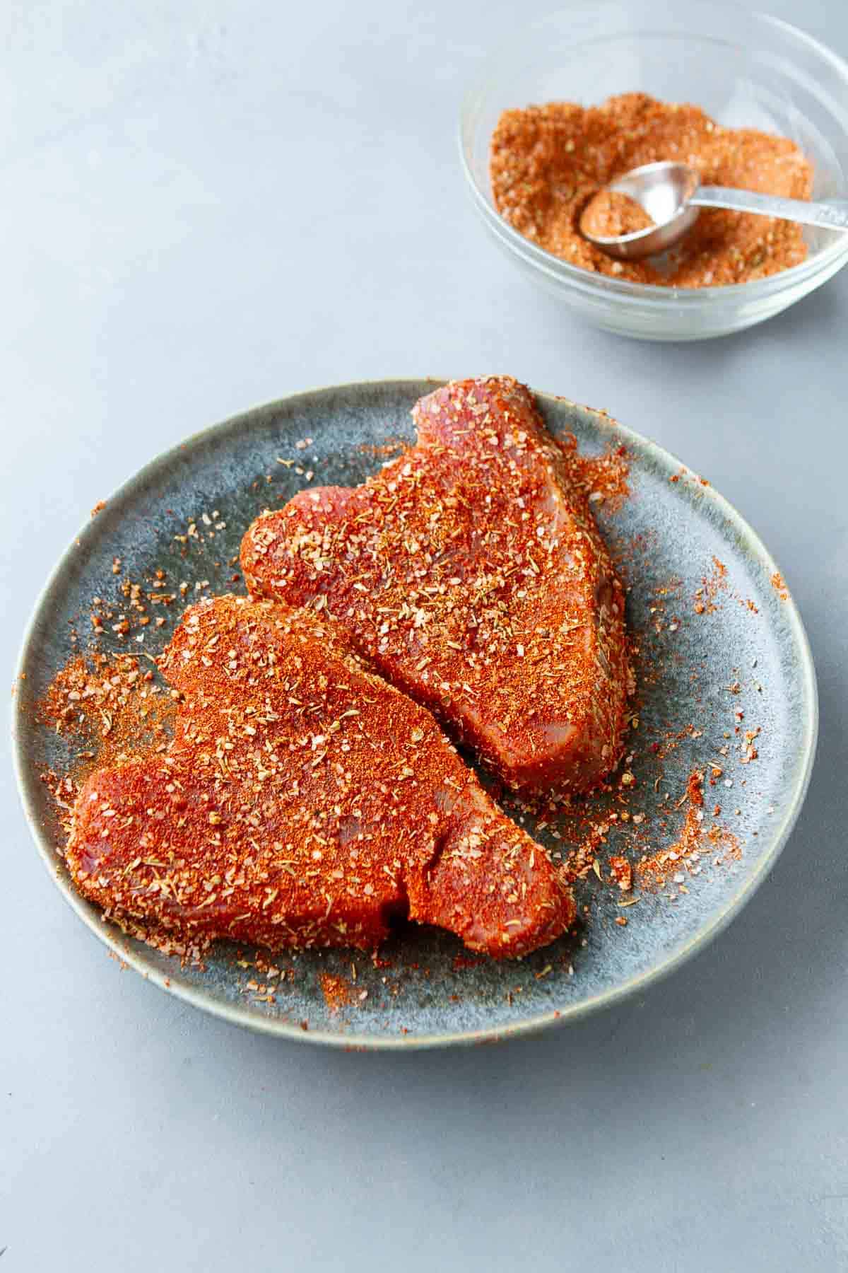 Spice-rubbed tuna steaks on a blue-gray plate.