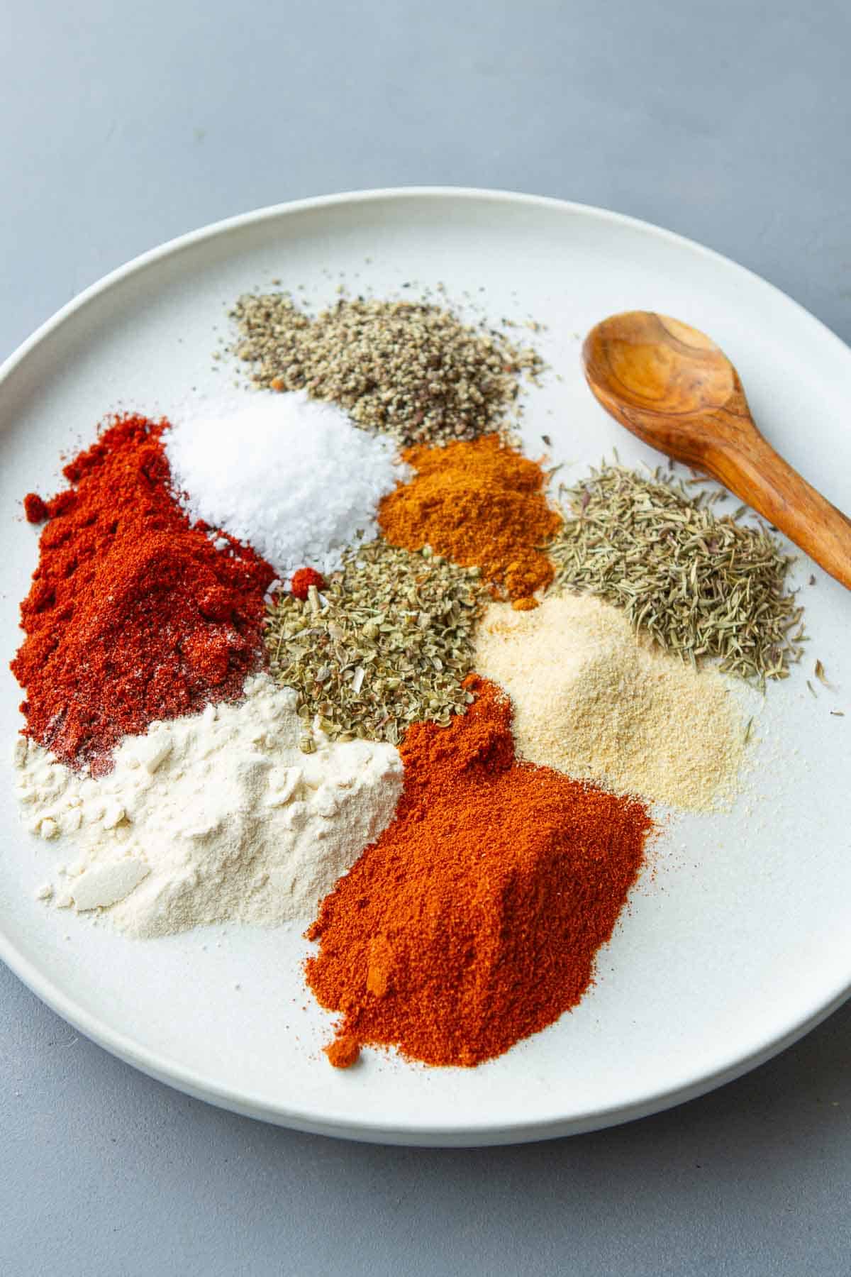Piles of herbs and spices on a white plate.