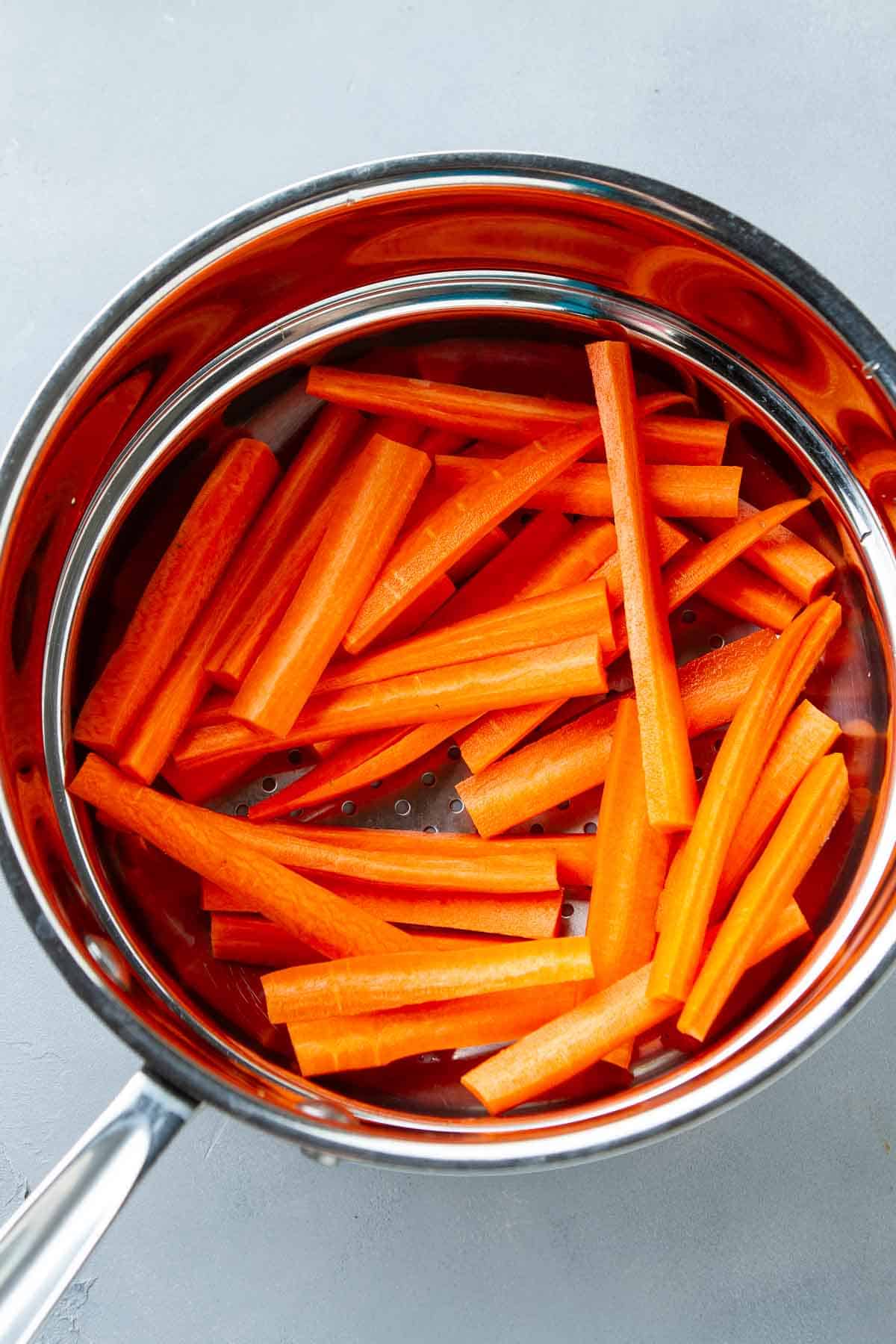Carrot sticks in a double boiler-style steamer.