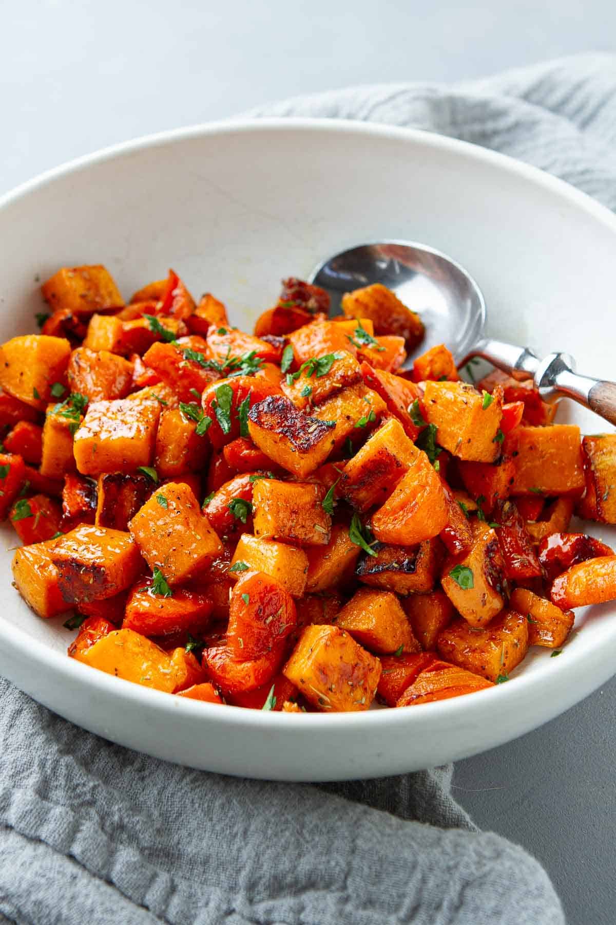 Roasted sweet potatoes and carrots in a white bowl.