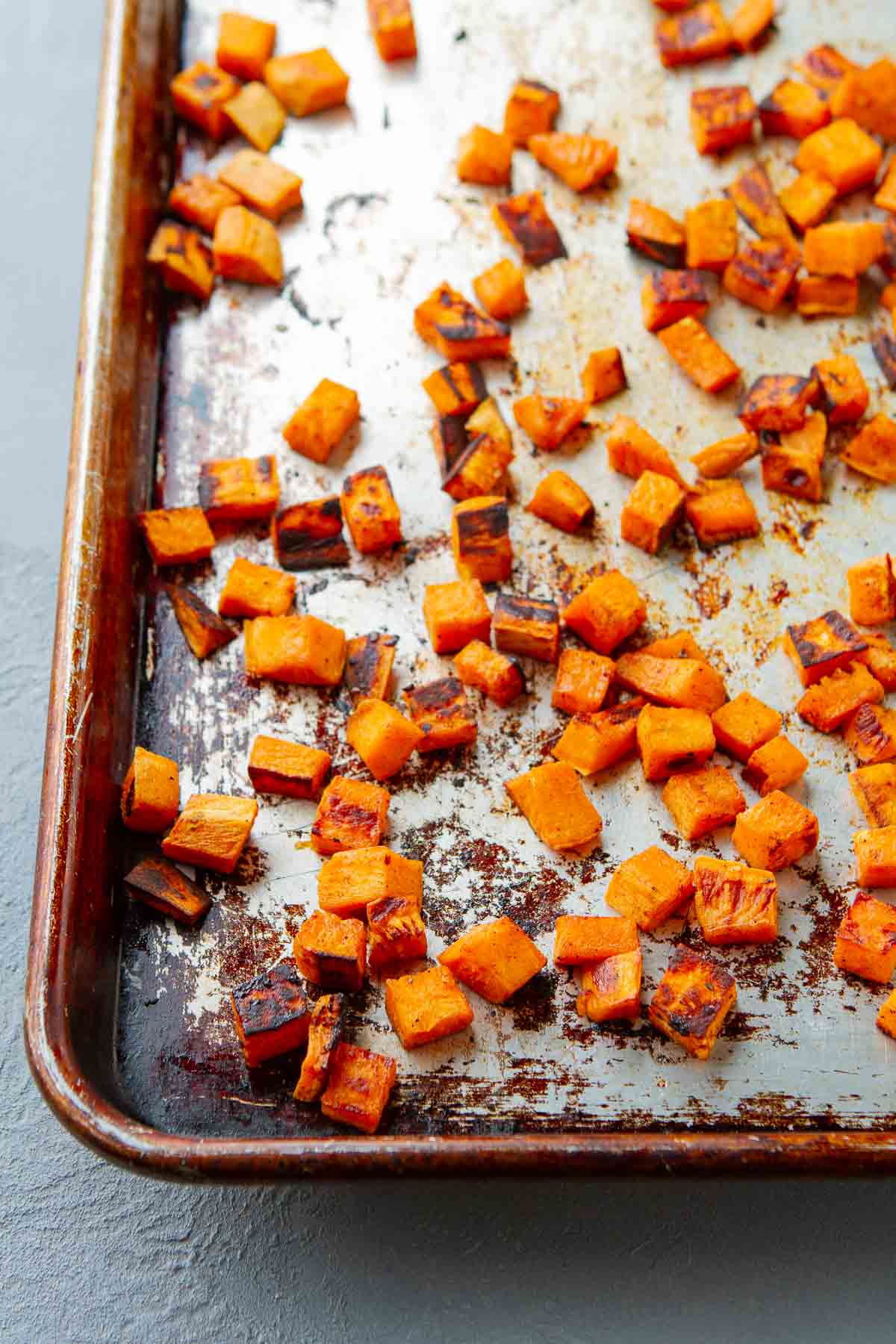 Roasted sweet potato cubes on a baking sheet.