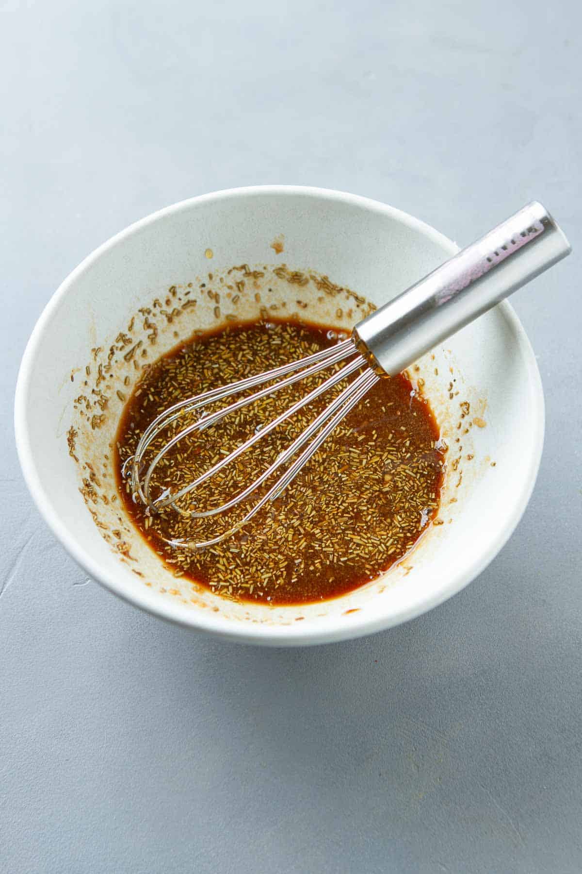 Salad dressing and a small whisk in a white bowl.