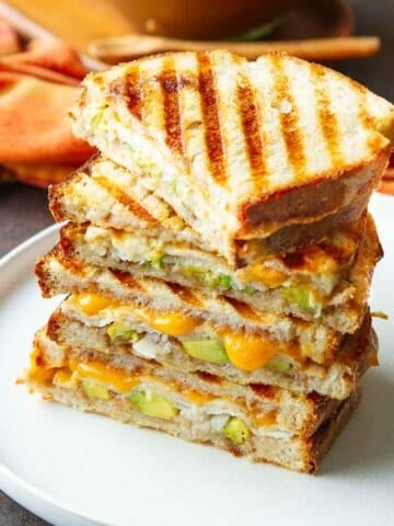 Two cut, stacked grilled turkey cheese sandwiches on a white plate.
