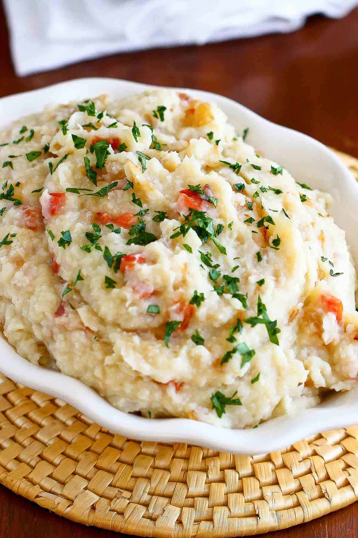 Mashed cauliflower and potatoes with peppers and onions in a serving dish.
