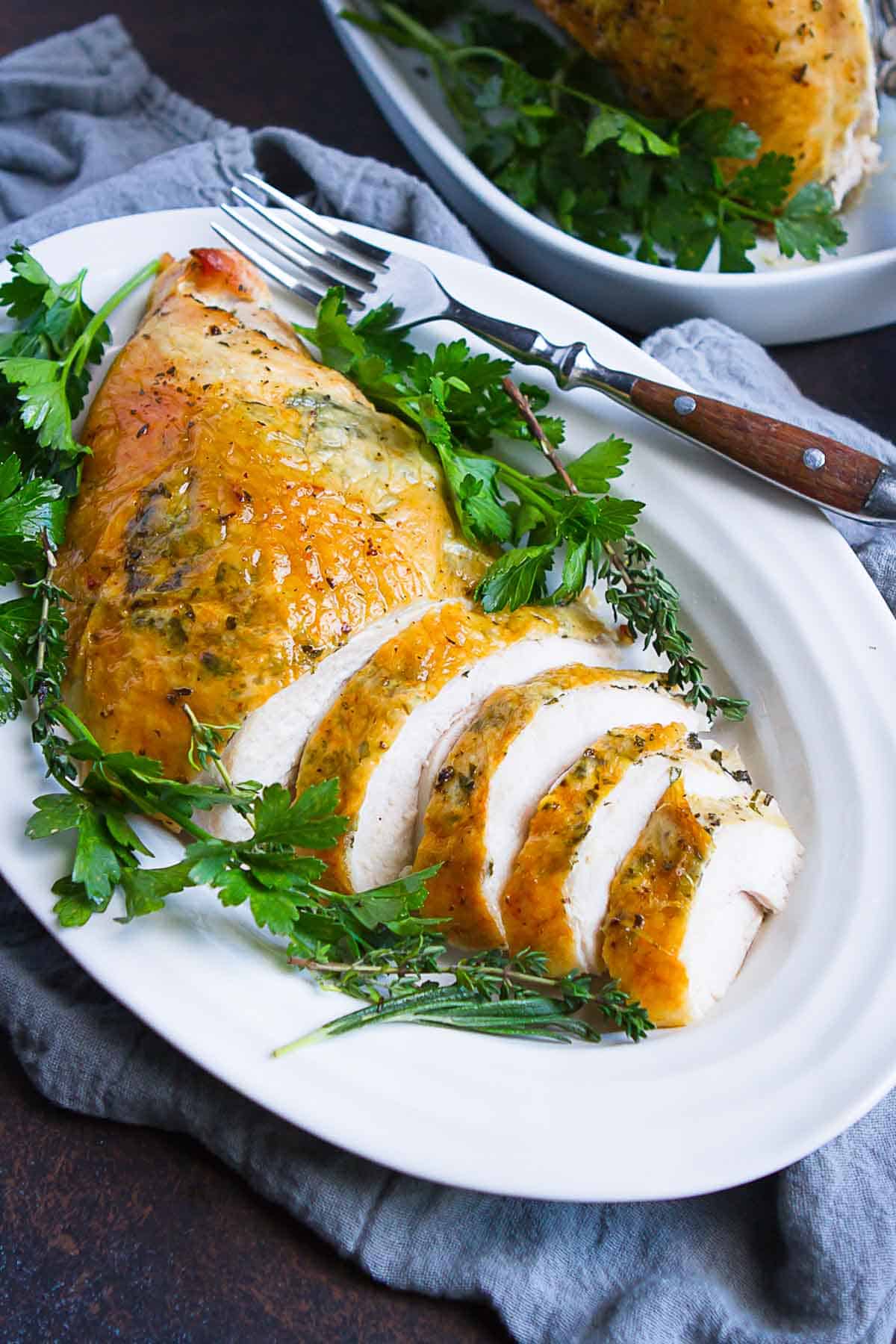 Sliced roasted turkey breast on a white platter.