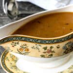 A white and yellow gravy boat filled with gravy.