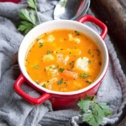 Winter vegetable soup with cauliflower and squash in a small red and white bowl.