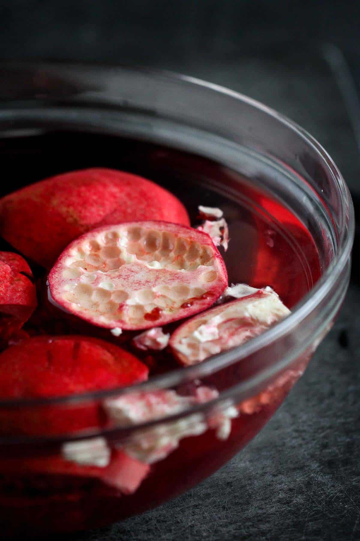 Pieces of pomegranate shell floating in a bowl of water.