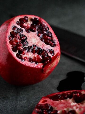 A cut pomegranate sitting on a black background.