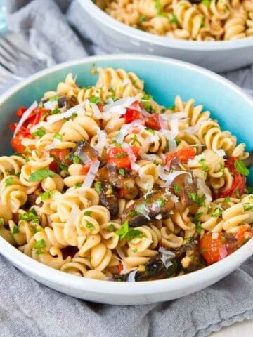 Pasta, roasted mushrooms and roasted tomatoes in a blue and white bowl.