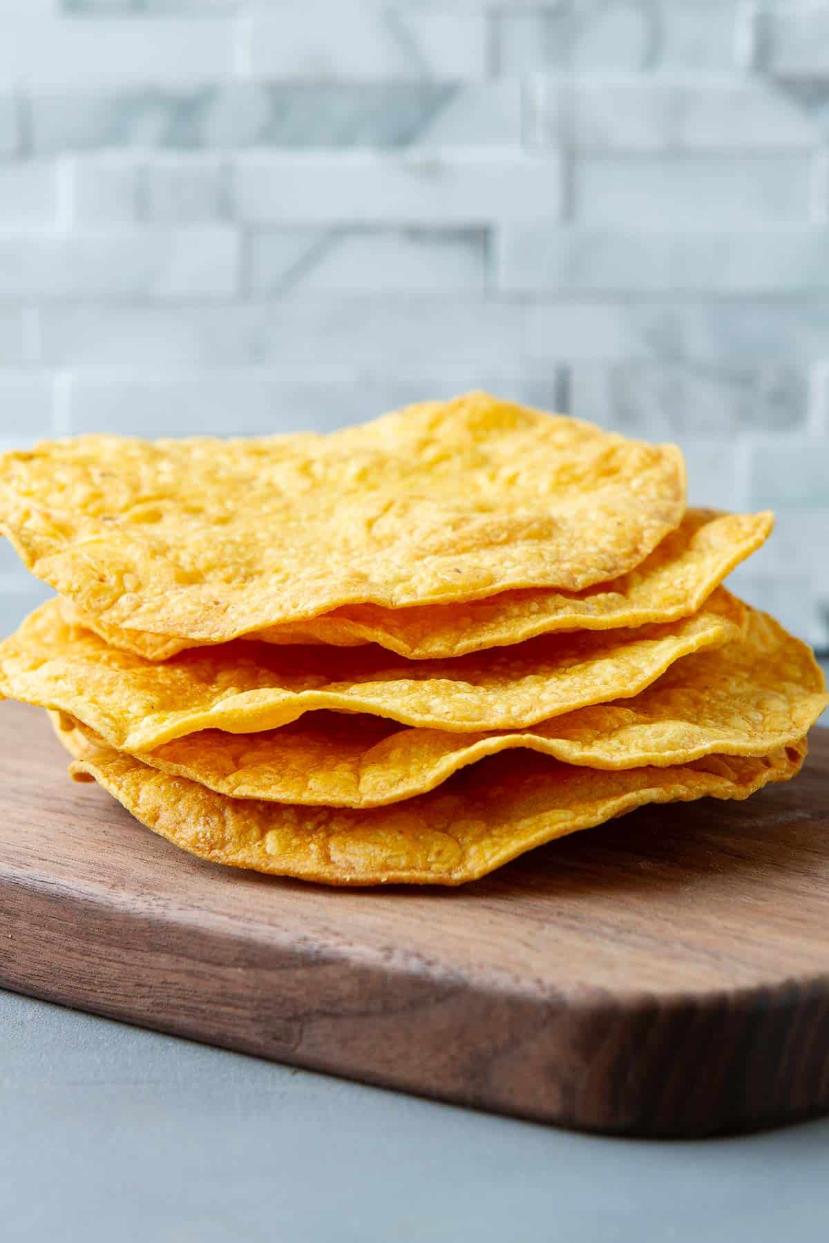 A stack of tostada shells on a cutting board.