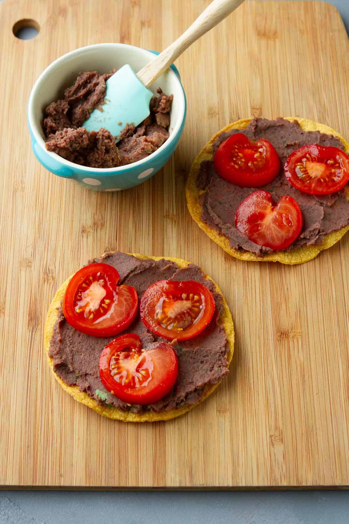 Tostadas shells topped with black bean dip and tomato slices.